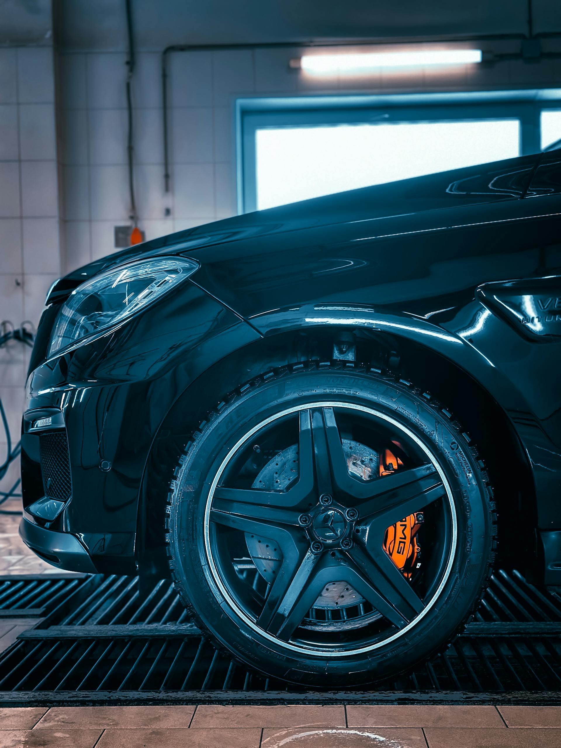 Detailed close-up of a luxury car wheel and brake system in a garage environment.