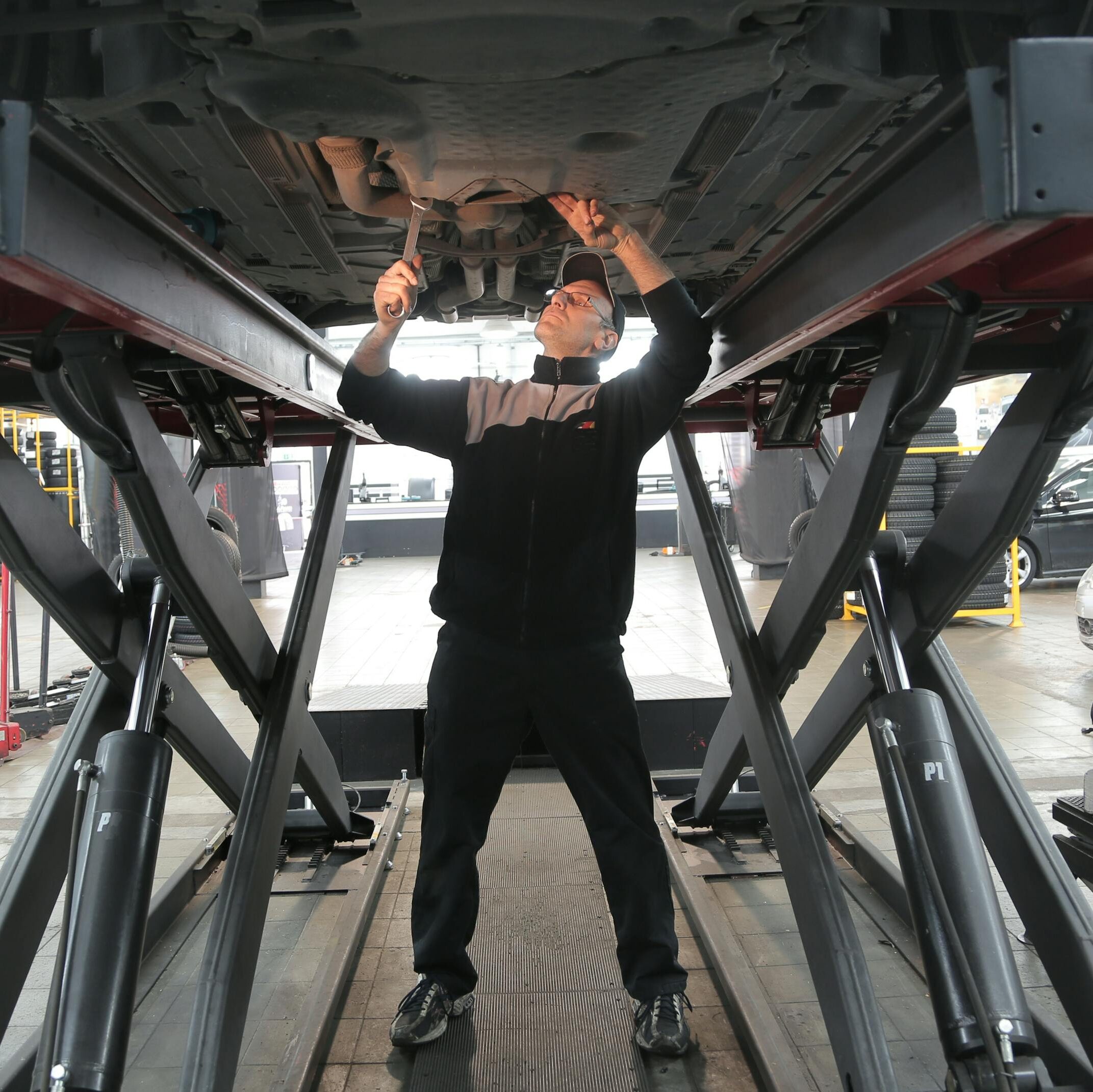 Mechanic inspecting and repairing a vehicle in a professional auto garage.